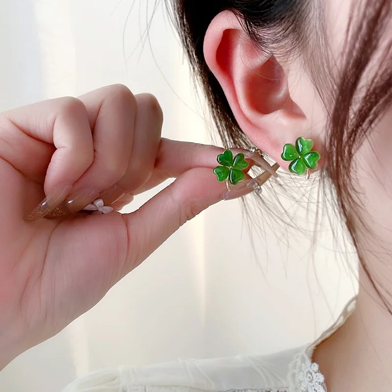 Arete trébol verde jade puesto y el par en la mano